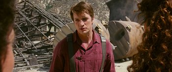Movie still from “Serenity” (2005), directed by Joss Whedon – A man in a red shirt is standing in front of a pile of rubble; Close Up shot, Over the shoulder angle