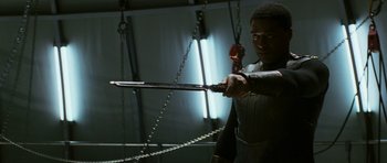 Movie still from “Serenity” (2005), directed by Joss Whedon – A man holding a sword with chains hanging from the ceiling; Medium shot, Low angle