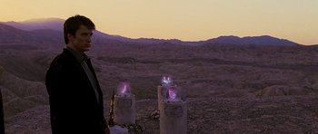 Movie still from “Serenity” (2005), directed by Joss Whedon – A man standing in front of a group of pillars with lights on them; Wide shot, Over the shoulder angle