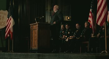 Movie still from “Serpico” (1973), directed by Sidney Lumet – A man standing at a podium speaking to a group of people; Wide shot, Low angle