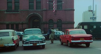 Movie still from “Serpico” (1973), directed by Sidney Lumet – An old car parked in front of a building; Extreme Wide shot, High angle