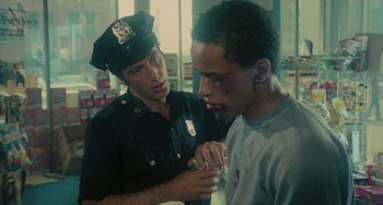 Movie still from “Serpico” (1973), directed by Sidney Lumet – A police officer looking at a young man's face; Medium shot, Over the shoulder angle