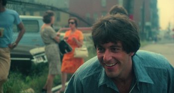 Movie still from “Serpico” (1973), directed by Sidney Lumet – A person smiling near other people; Close Up shot, Low angle