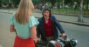 Movie still from “Serpico” (1973), directed by Sidney Lumet – A man sitting on a motorcycle talking to a woman; Medium shot, Over the shoulder angle