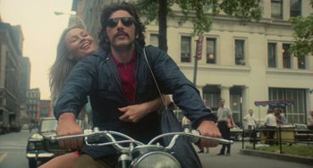 Movie still from “Serpico” (1973), directed by Sidney Lumet – A man and a woman riding a motorcycle down a street; Medium shot, Low angle