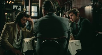 Movie still from “Serpico” (1973), directed by Sidney Lumet – A group of men sitting at a table in a restaurant; Medium shot, Over the shoulder angle