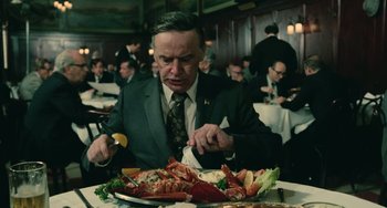 Movie still from “Serpico” (1973), directed by Sidney Lumet – A man sitting at a table with a plate of lobster; Medium shot, Over the shoulder angle