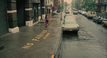 Movie still from “Serpico” (1973), directed by Sidney Lumet – A woman walking down a street next to a car; Extreme Wide shot, High angle