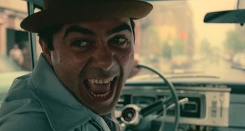 Movie still from “Serpico” (1973), directed by Sidney Lumet – A person in a car wearing a hat; Close Up shot, Low angle