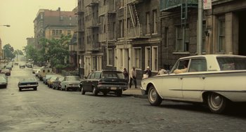 Movie still from “Serpico” (1973), directed by Sidney Lumet – An old photo of a street with cars parked on the side of the road; Extreme Wide shot, High angle