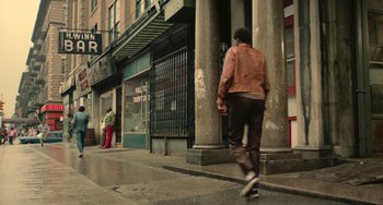 Movie still from “Serpico” (1973), directed by Sidney Lumet – A man riding a skateboard down the side of a street; Wide shot, Low angle