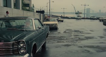 Movie still from “Serpico” (1973), directed by Sidney Lumet – Cars parked on the side of the road on a rainy day; Wide shot, High angle