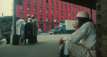 Movie still from “Serpico” (1973), directed by Sidney Lumet – A group of people sitting on the side of a road; Wide shot, Low angle