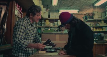 Movie still from “Serpico” (1973), directed by Sidney Lumet – A man and a woman are looking at a gun; Medium shot, Over the shoulder angle