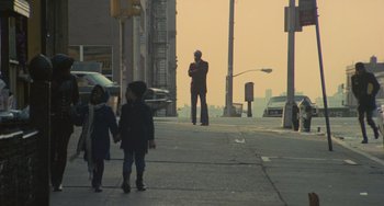 Movie still from “Serpico” (1973), directed by Sidney Lumet – A man standing on the side of a road with two children; Wide shot, Low angle
