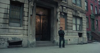 Movie still from “Serpico” (1973), directed by Sidney Lumet – A man standing in front of a building on a street; Wide shot, Low angle