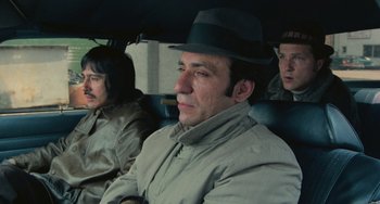 Movie still from “Serpico” (1973), directed by Sidney Lumet – A group of men riding in a car on a rainy day; Medium shot, High angle