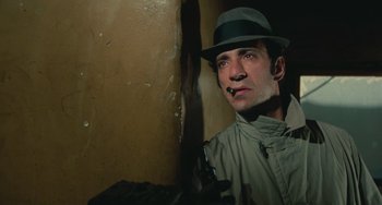 Movie still from “Serpico” (1973), directed by Sidney Lumet – A man wearing a hat and a trench coat; Close Up shot, Low angle