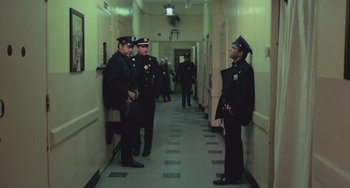 Movie still from “Serpico” (1973), directed by Sidney Lumet – A group of police officers standing next to each other in a hallway; Wide shot, High angle