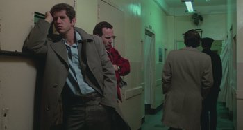 Movie still from “Serpico” (1973), directed by Sidney Lumet – A group of men standing next to each other in a hallway; Medium shot, Low angle