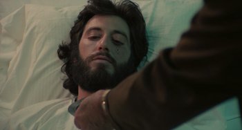 Movie still from “Serpico” (1973), directed by Sidney Lumet – A man with a beard is laying in a bed; Close Up shot, Over the shoulder angle