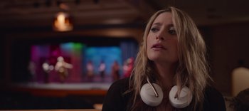 A woman with white headphones is sitting in a room