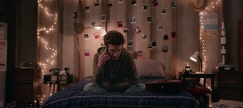 A man sitting on a bed talking on a cell phone
