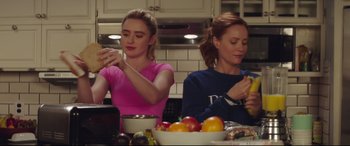 Movie still from “Blockers” (2018), directed by Kay Cannon – Two women sitting at a kitchen table preparing a meal; Medium shot, Over the shoulder angle