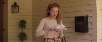 Movie still from “Blockers” (2018), directed by Kay Cannon – A woman standing in front of a wall holding papers; Medium shot, Over the shoulder angle