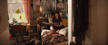 Movie still from “Blockers” (2018), directed by Kay Cannon – A woman sitting on a bed reading a book; Medium shot, High angle