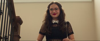 Movie still from “Blockers” (2018), directed by Kay Cannon – A young woman wearing glasses and a black and white dress; Medium shot, Over the shoulder angle