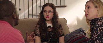 Movie still from “Blockers” (2018), directed by Kay Cannon – A woman sitting in a chair wearing a black dress; Medium shot, Over the shoulder angle