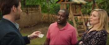 Movie still from “Blockers” (2018), directed by Kay Cannon – A man in a pink shirt is holding up a card; Medium shot, Over the shoulder angle