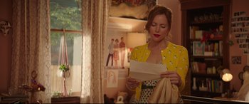 Movie still from “Blockers” (2018), directed by Kay Cannon – A woman holding a piece of paper while standing in a room; Medium shot, Over the shoulder angle