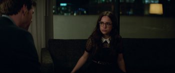 Movie still from “Blockers” (2018), directed by Kay Cannon – A woman sitting on top of a couch in a dark room; Medium shot, Over the shoulder angle