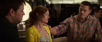 Movie still from “Blockers” (2018), directed by Kay Cannon – A woman in a yellow and white polka dot dress is being examined by a man in a plaid shirt; Medium shot, Over the shoulder angle