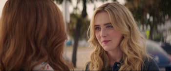 A woman with long blonde hair is looking at another woman with long blonde hair