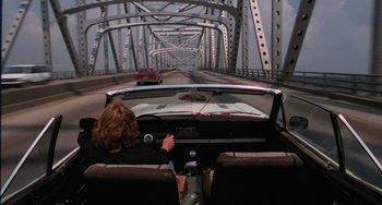 Movie still from “Sex, Lies, and Videotape” (1989), directed by Steven Soderbergh – A woman driving a car on a bridge; Wide shot, Over the shoulder angle