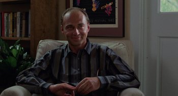 Movie still from “Sex, Lies, and Videotape” (1989), directed by Steven Soderbergh – A man sitting in a chair in front of a painting; Medium shot, Low angle