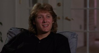 Movie still from “Sex, Lies, and Videotape” (1989), directed by Steven Soderbergh – A man with long blonde hair sitting on a couch; Close Up shot, Low angle