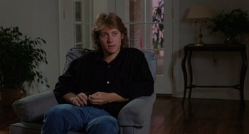 Movie still from “Sex, Lies, and Videotape” (1989), directed by Steven Soderbergh – A man sitting in a chair in front of a window; Medium shot, Over the shoulder angle