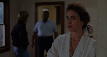 Movie still from “Sex, Lies, and Videotape” (1989), directed by Steven Soderbergh – A woman standing in front of two other people in a room; Medium shot, Over the shoulder angle