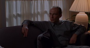 Movie still from “Sex, Lies, and Videotape” (1989), directed by Steven Soderbergh – A man sitting on top of a couch in front of a window; Medium shot, Low angle