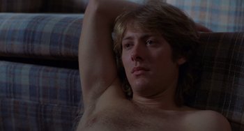 Movie still from “Sex, Lies, and Videotape” (1989), directed by Steven Soderbergh – A shirtless man with long brown hair is sitting on a couch; Close Up shot, Low angle