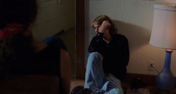 Movie still from “Sex, Lies, and Videotape” (1989), directed by Steven Soderbergh – A man sitting on the floor with his hand on his face; Medium shot, Over the shoulder angle