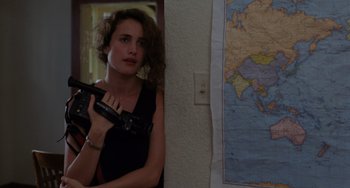 Movie still from “Sex, Lies, and Videotape” (1989), directed by Steven Soderbergh – A woman holding a gun in a room with a map on the wall; Close Up shot, High angle