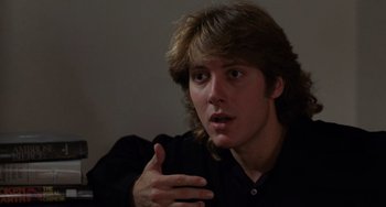 Movie still from “Sex, Lies, and Videotape” (1989), directed by Steven Soderbergh – A young man with long brown hair talking to someone in a dark room; Close Up shot, Over the shoulder angle