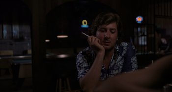 Movie still from “Sex, Lies, and Videotape” (1989), directed by Steven Soderbergh – A man sitting at a table with a cigarette in his mouth; Medium shot, Over the shoulder angle