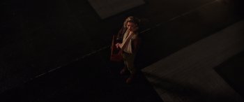 Movie still from “Shadow in the Cloud” (2020), directed by Roseanne Liang – A woman standing on the sidewalk holding a bag; Wide shot, High angle