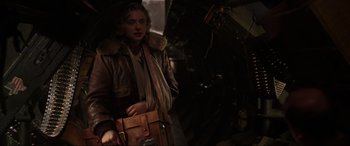 Movie still from “Shadow in the Cloud” (2020), directed by Roseanne Liang – A man in a brown jacket holding a brown bag; Medium shot, Low angle